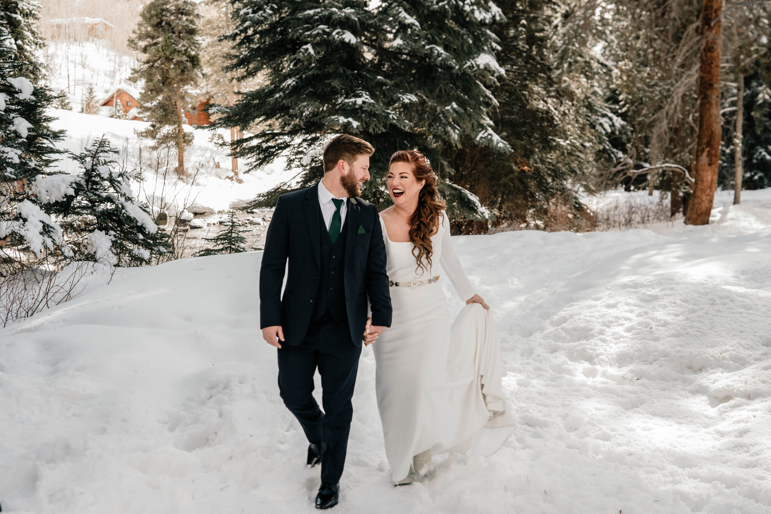 Couple holding hands walking in the snow outside of Vail.