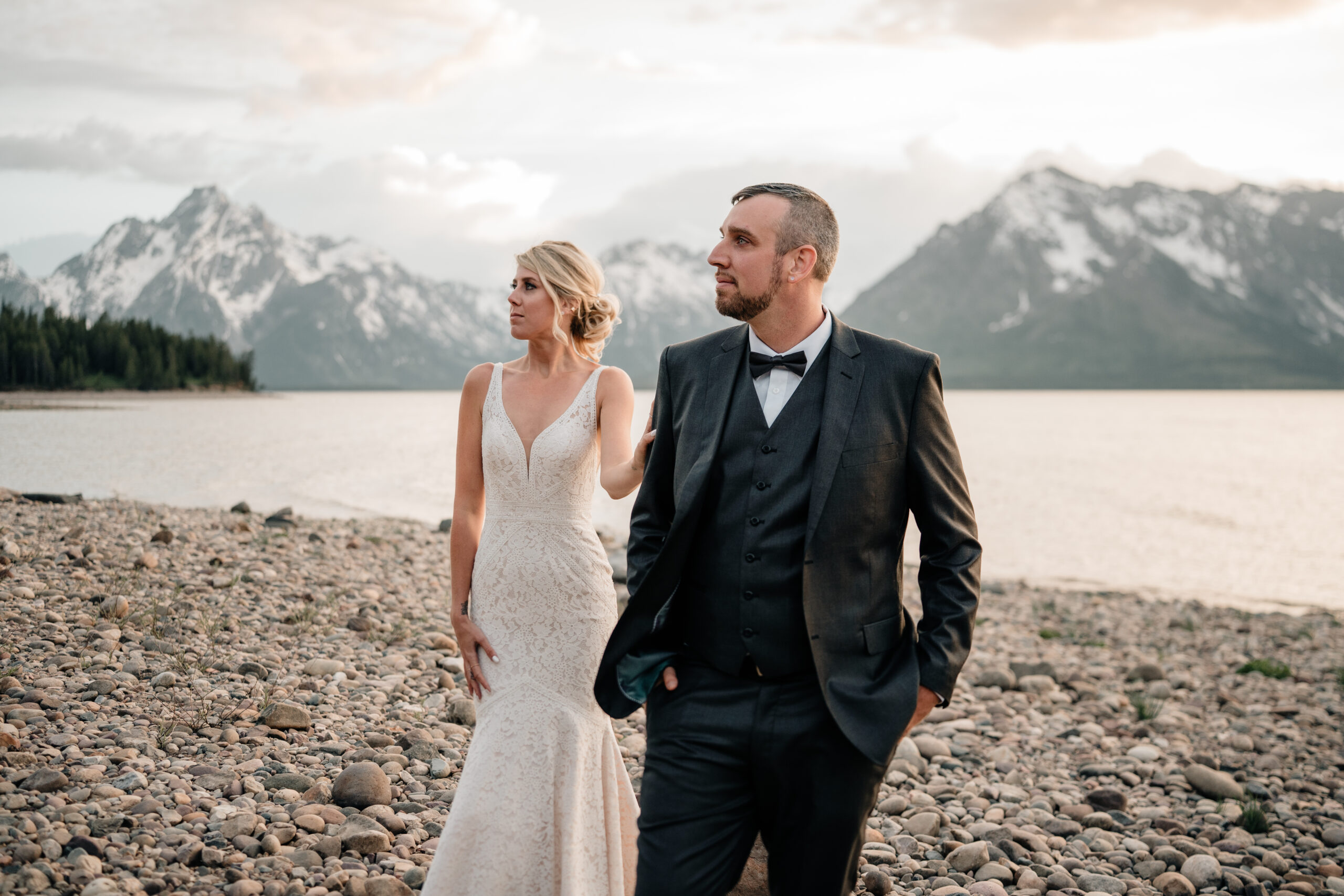 Couple poses in front of the Grand Tetons mountains in wedding attire. 