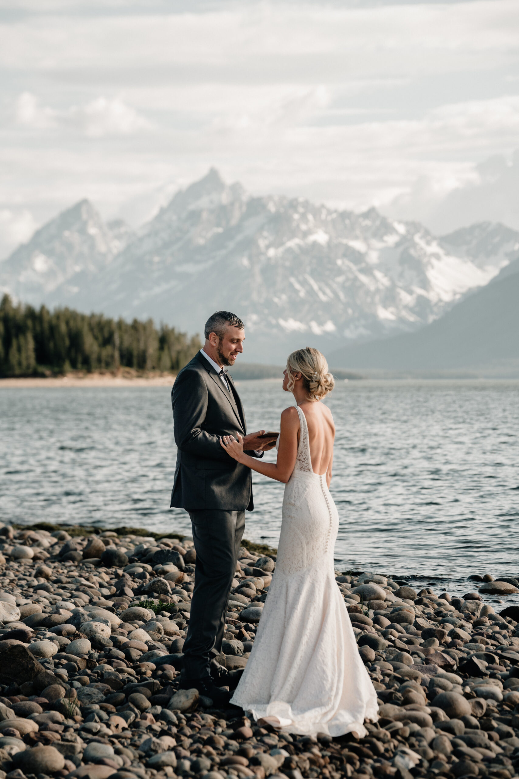 Couple exchanges vows at Colter Bay Swim Beach in front of the mountains and lake. 
